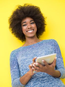 Young Happy African American Woman Using Digital Tablet  Isolated on a yellow background