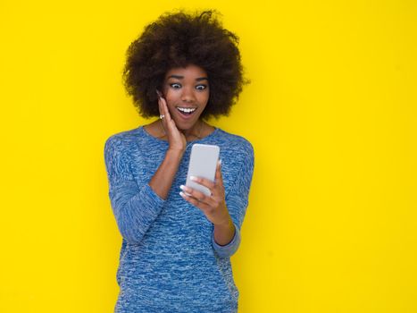 Young Happy African American Woman Using mobile phone  Isolated on a yellow background