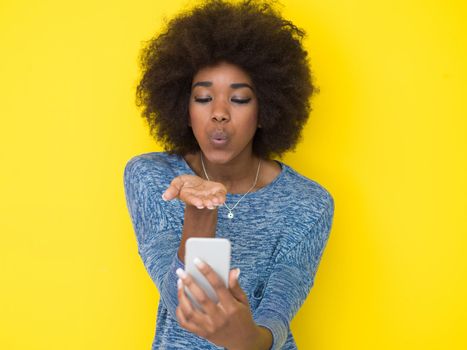 Young Happy African American Woman Using mobile phone  Isolated on a yellow background