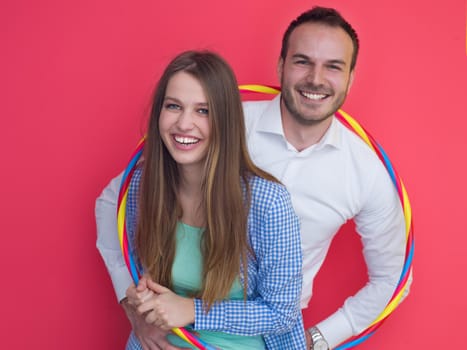 portrait of happy couple with hula hoop isolated on red background