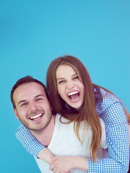 happy young man piggybacking his girlfriend isolated on blue background