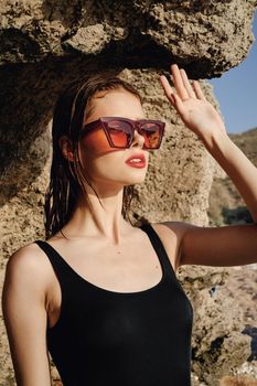 woman wearing sunglasses swimsuit dispensing rocks travel. High quality photo