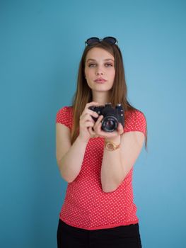 portrait of a smiling pretty girl taking photo on a retro camera isolated over blue background