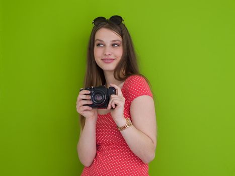 portrait of a smiling pretty girl taking photo on a retro camera isolated over green background