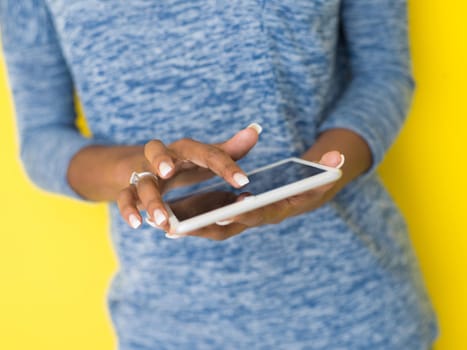 Young Happy African American Woman Using Digital Tablet  Isolated on a yellow background
