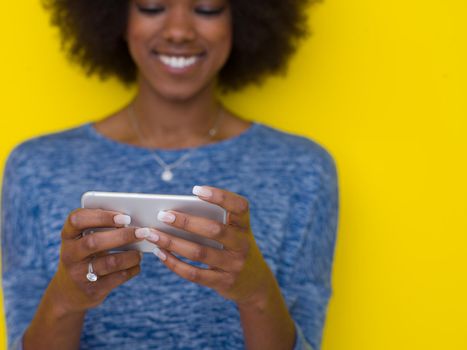 Young Happy African American Woman Using mobile phone  Isolated on a yellow background