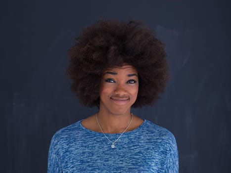 portrait of a beautiful friendly African American woman with a curly afro hairstyle and lovely smile sitting isolated on a gray background