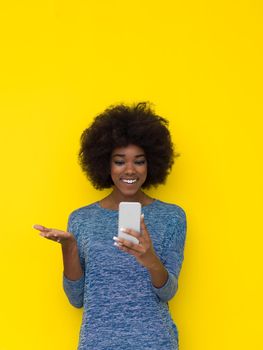 Young Happy African American Woman Using mobile phone  Isolated on a yellow background