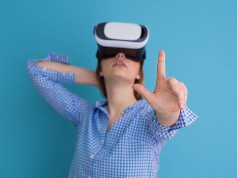 Happy girl getting experience using VR headset glasses of virtual reality, isolated on blue background