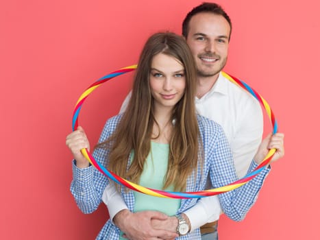 portrait of happy couple with hula hoop isolated on red background