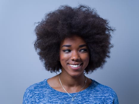 portrait of a beautiful friendly African American woman with a curly afro hairstyle and lovely smile isolated on a gray background