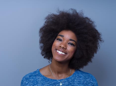 portrait of a beautiful friendly African American woman with a curly afro hairstyle and lovely smile isolated on a gray background