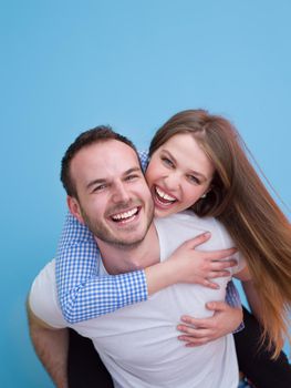 happy young man piggybacking his girlfriend isolated on blue background