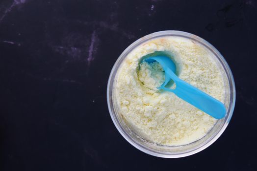 Close up of baby milk powder and spoon on tile background