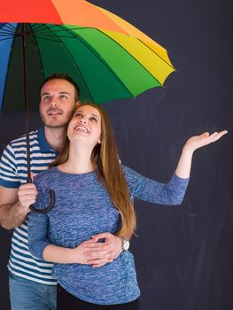 portrait of a beautiful loving young couple with a colorful umbrella isolated on a gray background