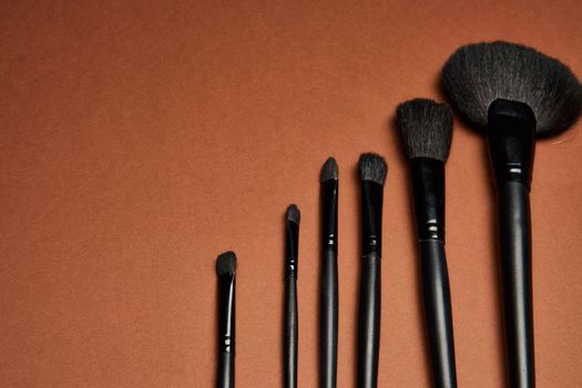makeup brushes mascara accessories glamor brown background. High quality photo