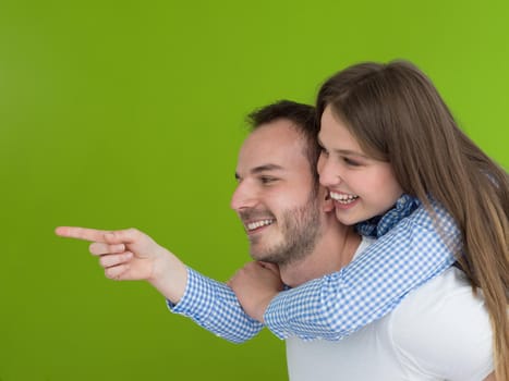 happy young man piggybacking his girlfriend isolated on green background