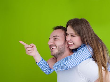happy young man piggybacking his girlfriend isolated on green background