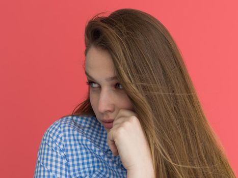 Portrait of a beautiful positive young woman while playing with her long silky hair isolated on red background