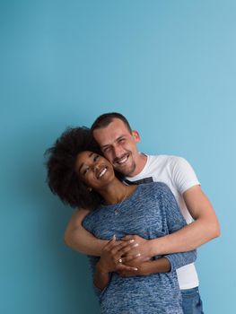 Young happy multiethnic couple laughing and hugging isolated on a blue background