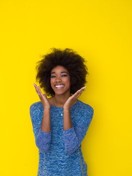 portrait of a beautiful friendly African American woman with a curly afro hairstyle and lovely smile isolated on a Yellow background