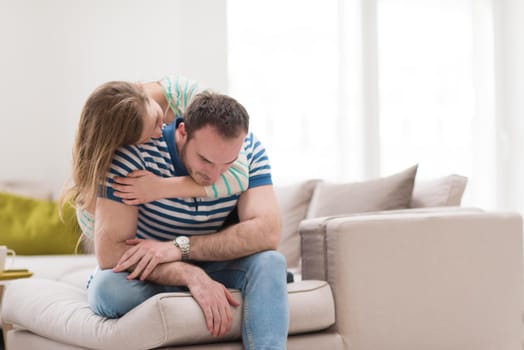 young handsome couple enjoys hugging on the sofa in their luxury home villa