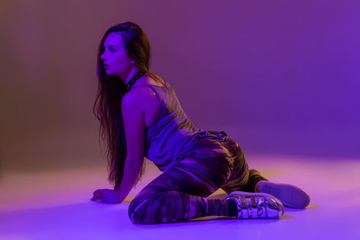 Attractive young blonde woman in the studio dancing Booty dance on a pink background. Color filters
