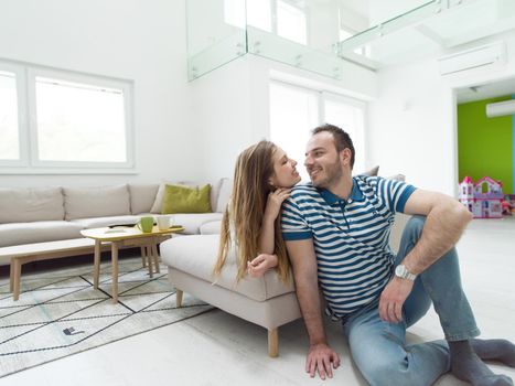 young handsome couple enjoys hugging on the sofa in their luxury home villa