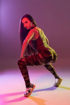 Attractive young blonde woman in the studio dancing Booty dance on a pink background. Color filters
