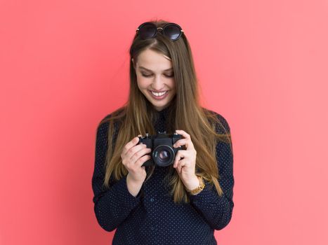 portrait of a smiling pretty girl taking photo on a retro camera isolated over red background