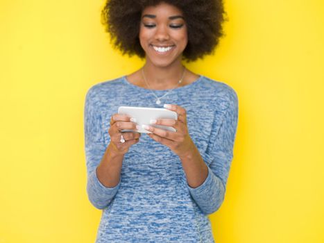Young Happy African American Woman Using mobile phone  Isolated on a yellow background