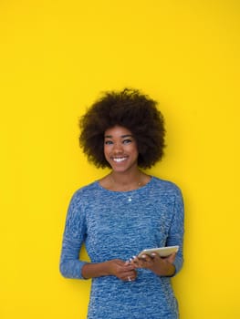 Young Happy African American Woman Using Digital Tablet  Isolated on a yellow background