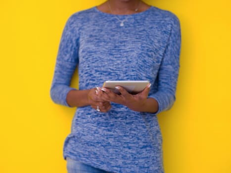 Young Happy African American Woman Using Digital Tablet  Isolated on a yellow background