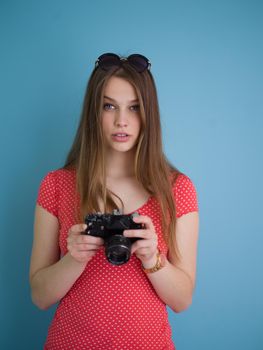 portrait of a smiling pretty girl taking photo on a retro camera isolated over blue background