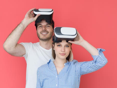 happy young couple getting experience using VR-headset glasses of virtual reality isolated over red background
