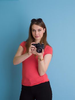 portrait of a smiling pretty girl taking photo on a retro camera isolated over blue background