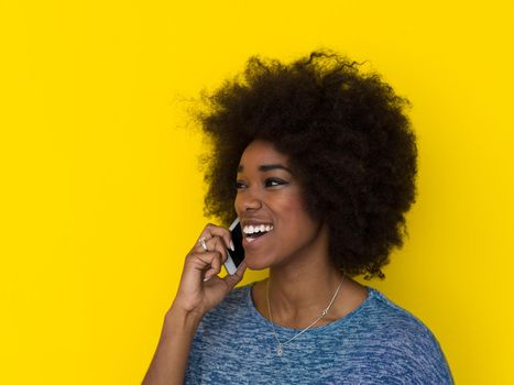 Young Happy African American Woman Using mobile phone  Isolated on a yellow background