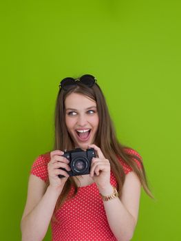 portrait of a smiling pretty girl taking photo on a retro camera isolated over green background