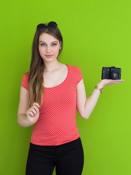 portrait of a smiling pretty girl taking photo on a retro camera isolated over green background