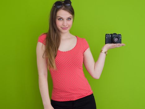 portrait of a smiling pretty girl taking photo on a retro camera isolated over green background