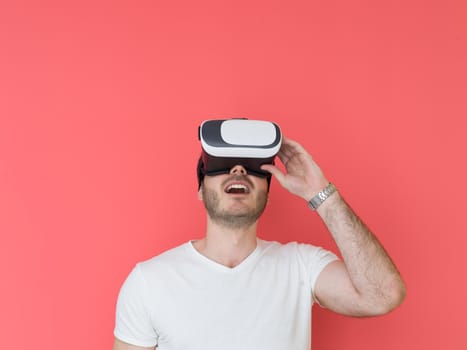 Happy man getting experience using VR headset glasses of virtual reality, isolated on red background