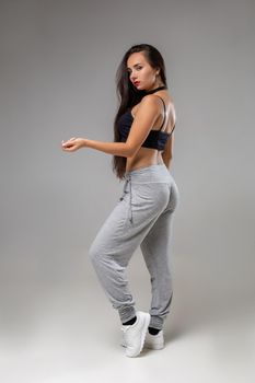 Modern dancer poses in front of the gray studio background. Modern dance styles, dancehall, jazz funk, hip hop