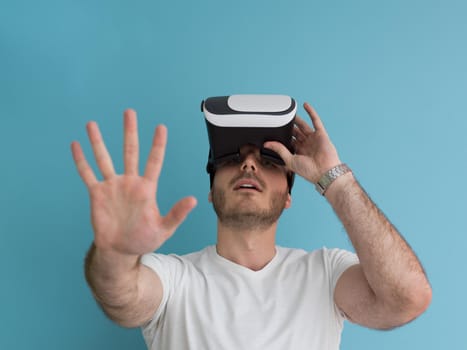Happy man getting experience using VR headset glasses of virtual reality, isolated on blue background
