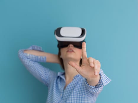 Happy girl getting experience using VR headset glasses of virtual reality, isolated on blue background