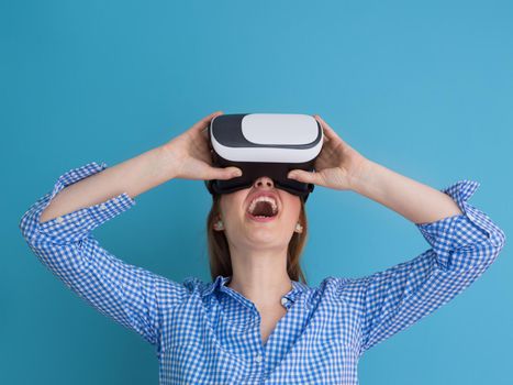 Happy girl getting experience using VR headset glasses of virtual reality, isolated on blue background