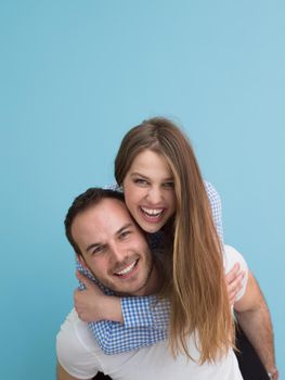 happy young man piggybacking his girlfriend isolated on blue background