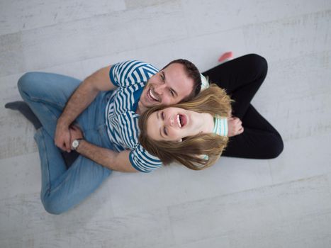 top view of Cheerful young couple sitting with back to each other on floor