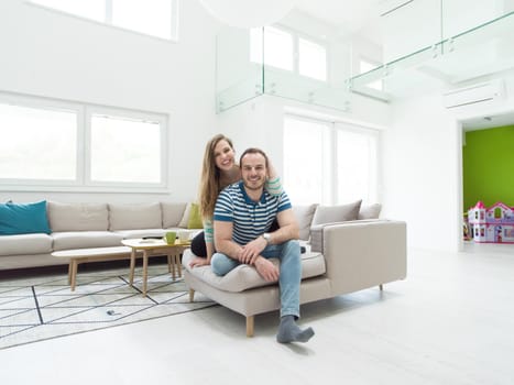 young handsome couple enjoys hugging on the sofa in their luxury home villa