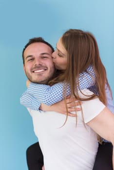 happy young man piggybacking his girlfriend isolated on blue background