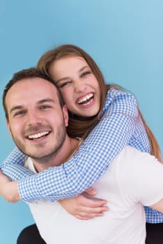 happy young man piggybacking his girlfriend isolated on blue background